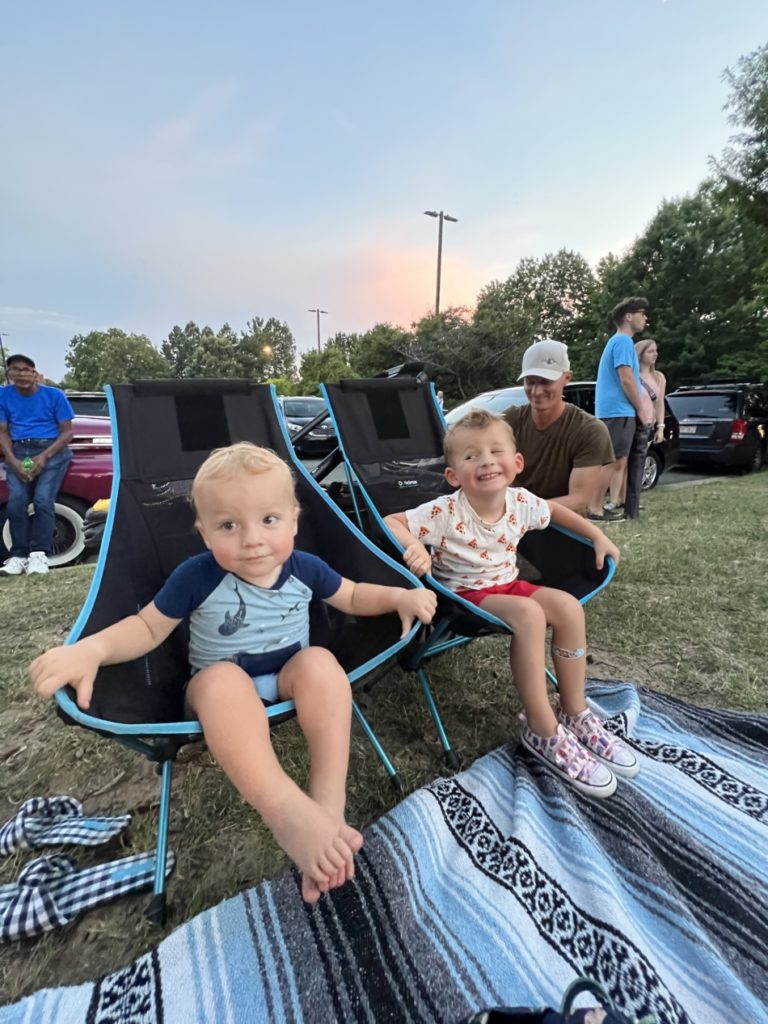 Toddlers sitting in a portable camping chairs at 4th of July celebration