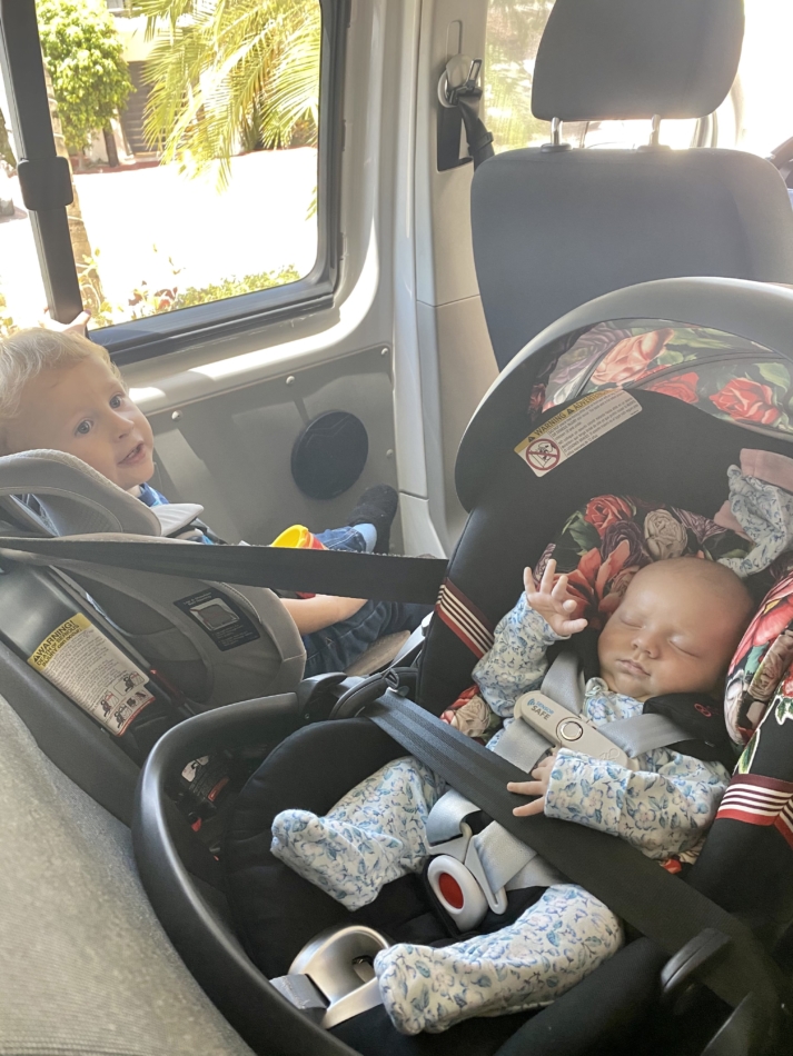Toddler nad baby traveling to the airport in their travel car seats