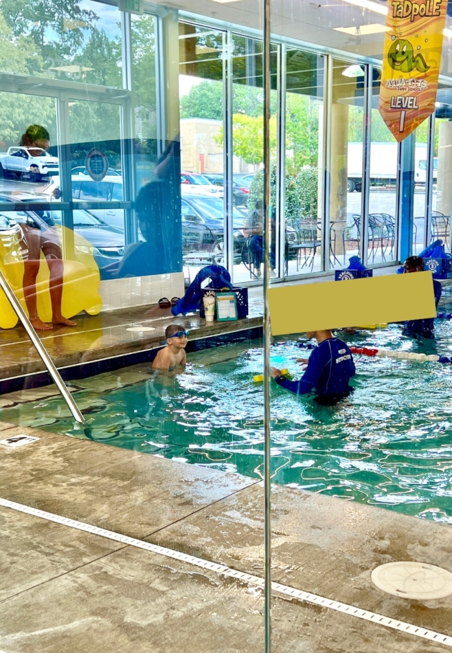 Toddler sitting in the pool with a swim instructor